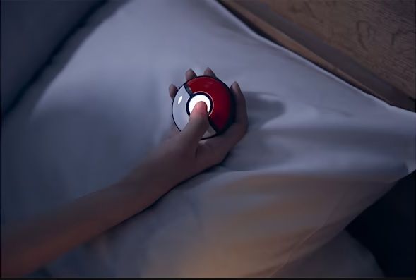Sosteniendo el dispositivo Pokemon GO Plus+ en la cama