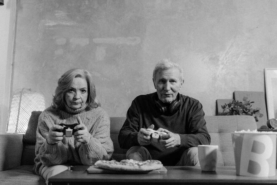 Foto en escala de grises de un anciano y una mujer jugando videojuegos